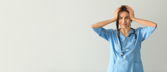 Stressed female nurse on light background