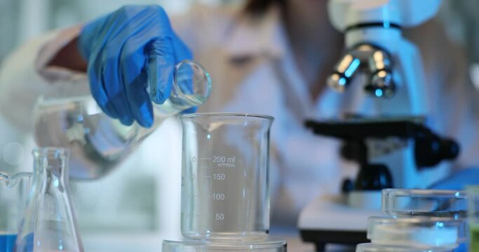 Scientist carefully pours the clear liquid into flask