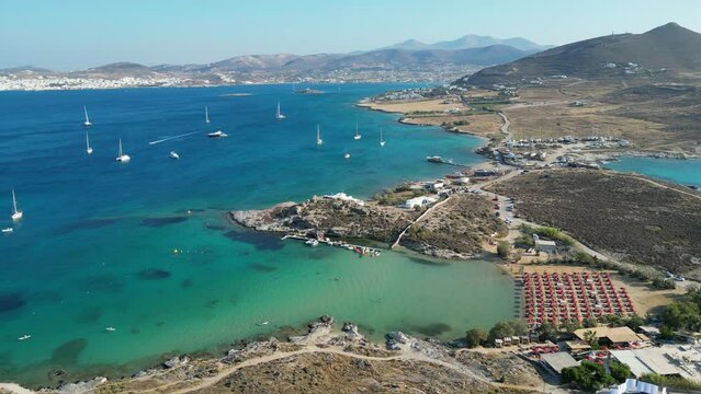 Aerial footage of turquoise waters and a small beach club on the island of Paros, one of the many Cyclades Islands in the Aegean Sea.