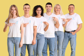 Fototapeta premium People pointing at blue awareness ribbons on yellow background. World Cancer Day