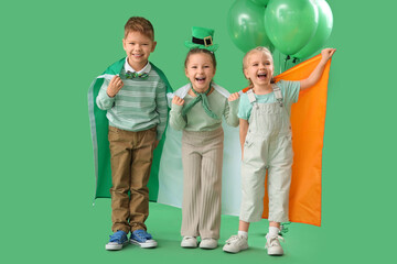 Cute kids with balloons and flag of Ireland on green background. St. Patrick's Day celebration