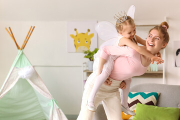 Cute little girl dressed as fairy with her mother having fun at home