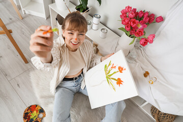 Female artist painting flowers on canvas in workshop