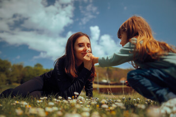 Mother Smelling Beautiful Flowers from her Daughter. Happy mom and daughter celebrating together outdoors
