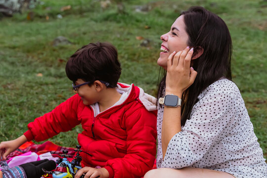 International Children Day. Latina mother having fun with her young children outdoors. Sitting on the ground watching the scenery. Concept of family and togetherness. Single mother of two children. - Powered by Adobe