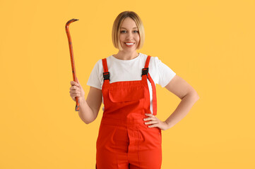 Female worker with crowbar on yellow background
