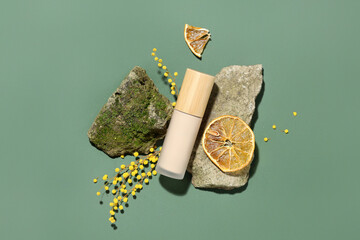 Makeup foundation with stones, moss and orange slices on green background. Eco style concept