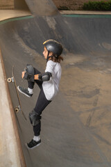 Boy riding his skateboard up the ramp at the skateboard park
