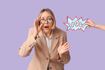Shocked adult woman and female hand holding speech bubble with word WOW on lilac background