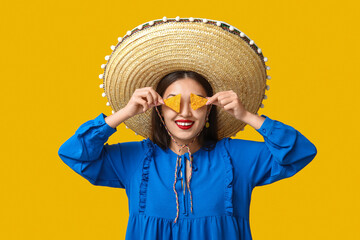 Portrait of young woman with sombrero and tortilla chips on yellow background. National Tortilla...