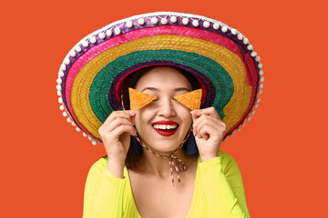 Portrait of young woman with sombrero and tortilla chips on orange background. National Tortilla...