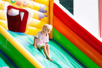 Child jumping on playground trampoline. Kids jump. - obrazy, fototapety, plakaty
