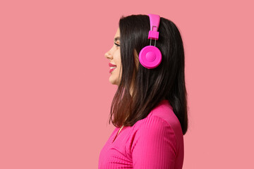 Beautiful young woman in modern headphones on pink background