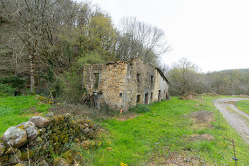 abandoned and isolated semi-demolished stone house in the middle of the mountain next to a country road