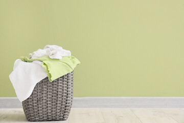 Laundry basket with dirty clothes near green wall