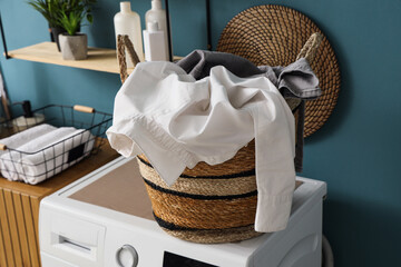Wicker basket with dirty clothes on washing machine in room