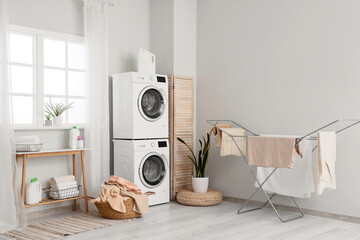 Interior of laundry room with washing machines, basket and dryer