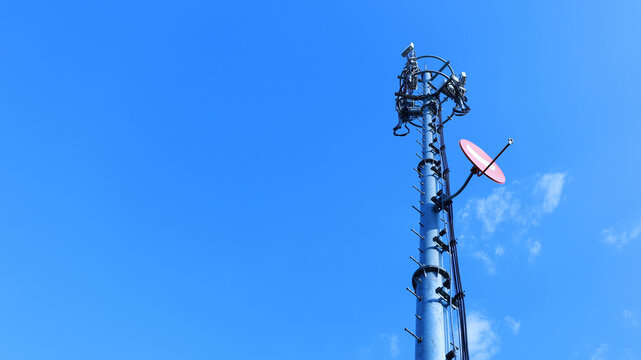 4G and 5G cell monopole. Satellite dish on cell tower with antenna for cellular network on metal in bottom view against blue sky with copy space with selective focus.
