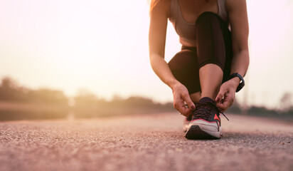 Running shoes, closeup of woman tying shoe laces. Female sport fitness runner getting ready for jogging outdoors - Powered by Adobe