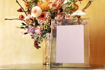 Blank pink frame by flower vase, yellow room interior design