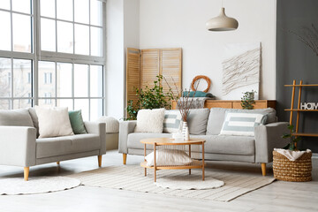 Interior of modern living room with sofas, table and willow branches in vase