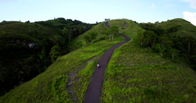 Scooter driving uphill at Teletubbies Hills of Nusa Penida, Bali. Aerial