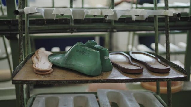Various stages of sandal assembly on a factory rack