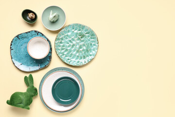 Stylish table setting with Easter eggs and toy bunnies on light yellow background