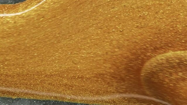 Glitter fluid spill. Shimmering texture. Blur golden color shiny texture liquid ink drip on silver gray luxury abstract art background.