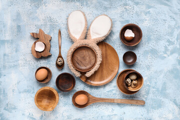 Stylish table setting with Easter eggs and wooden bunny on blue grunge background