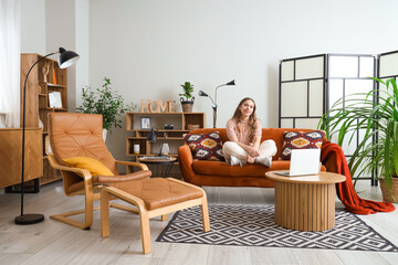 Young woman sitting on red sofa at home