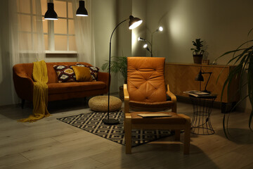 Interior of dark living room with armchair and glowing lamps at night
