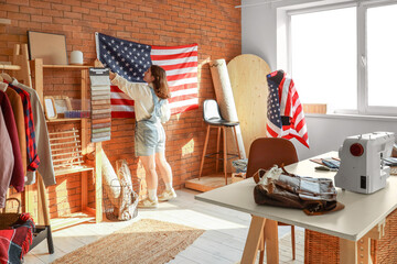 Young tailor with hanging USA flag on wall in atelier