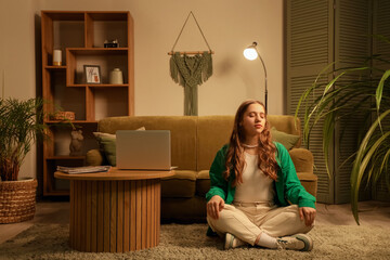 Young woman meditating on carpet at home in evening