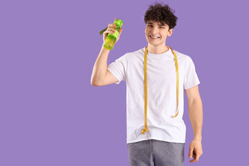 Fototapeta na wymiar Handsome young happy sporty man with measuring tape and bottle of water on purple background. Weight loss concept