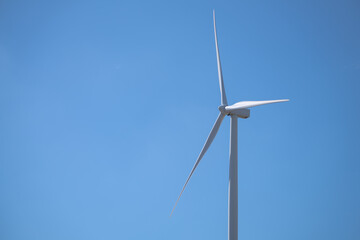 Wind turbine is standing tall in blue sky, Wind energy. Wind power. Sustainable, renewable energy....