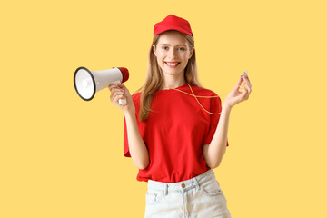 Young pretty female lifeguard in cap with whistle and megaphone on yellow background