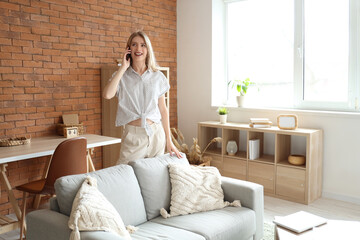 Young pretty woman talking with mobile phone in living room