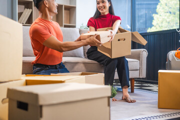 Young Asian couple relocating to a new house, joyfully packing and unpacking belongings. Expertise...