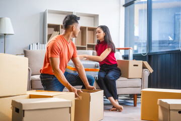 Young Asian couple relocating to a new house, joyfully packing and unpacking belongings. Expertise...