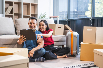Young Asian couple relocating to a new house, joyfully packing and unpacking belongings. Expertise...