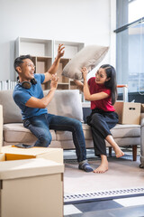 Young Asian couple relocating to a new house, joyfully packing and unpacking belongings. Expertise in moving, packing, togetherness, and creating a new home together.