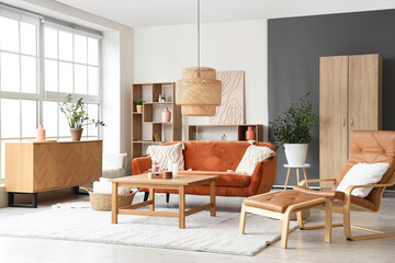 Stylish interior of living room with comfortable sofa, lamp, armchair and coffee table