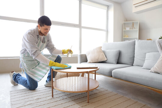 Young bearded man cleaning table at home