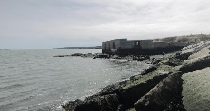Old war time bunker and ocean lookout on the rocky shores of the Atlantic Ocean in Portland Maine during a overcast day in 4k.