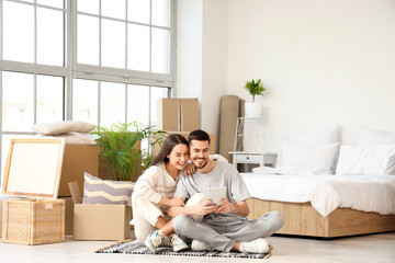Young couple using tablet computer in bedroom on moving day