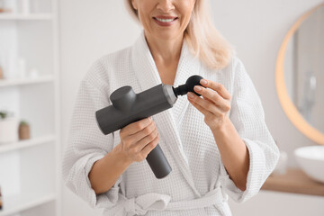Mature woman with percussive massager in bathroom, closeup