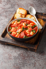 Slow cooked stew of butter beans, chorizo and spinach in tomato sauce close-up in a bowl on the table. Vertical