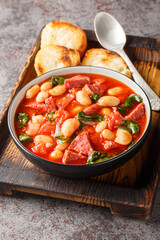 Chorizo, butter bean and spinach stew close-up in a bowl served with toasted bread on the table. Vertical