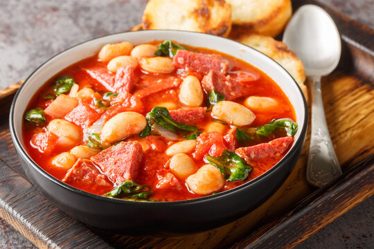 Spanish stew of butter beans, chorizo and spinach in tomato sauce close-up in a bowl on the table. Horizontal